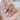 Makur Morganite Engagement Ring | R862-4 featuring a pear-shaped stone with a diamond halo on a finger with long light pink nails.