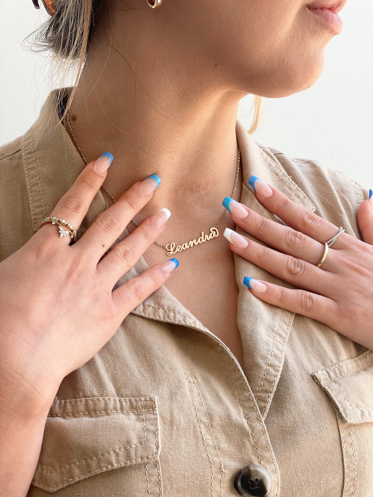 A gold Bridgette | 14K Yellow Gold Nameplate Pendant in cursive reading Leandra worn around a person’s neck on an 18 inch chain.