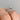 Side view of a Petite Crescent | Round Solitaire Engagement Ring - HT2559RD7W on a finger, featuring a round solitaire diamond and an intricate metal band.