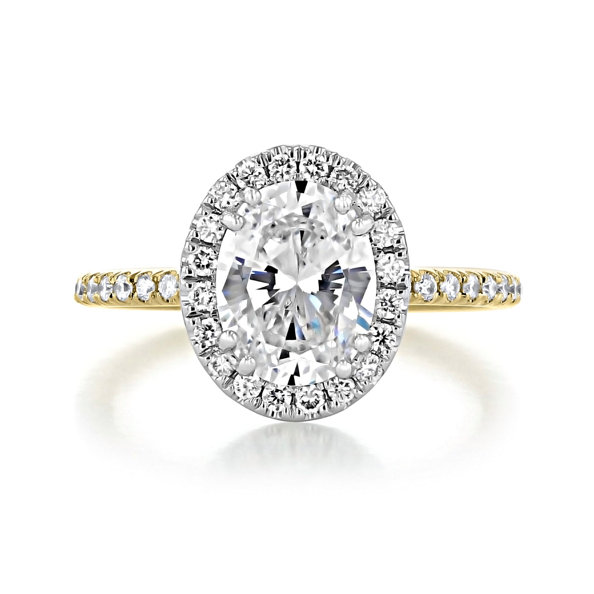 Mae Oval Halo Two-Toned Engagement Ring featuring an oval-shaped center gemstone with a diamond halo on a thin two-toned gold band with pavé diamonds.