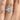 A Tacori Dantela | Princess 3-Stone Engagement Ring - 2663PR7W featuring a cushion-cut center diamond flanked by two baguette diamonds on a diamond-encrusted band worn on a finger.
