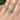 Miramar | Oval Prong-Set Engagement Ring featuring an oval-cut diamond with a hidden halo and small round side stones on a yellow gold band, worn on a finger.