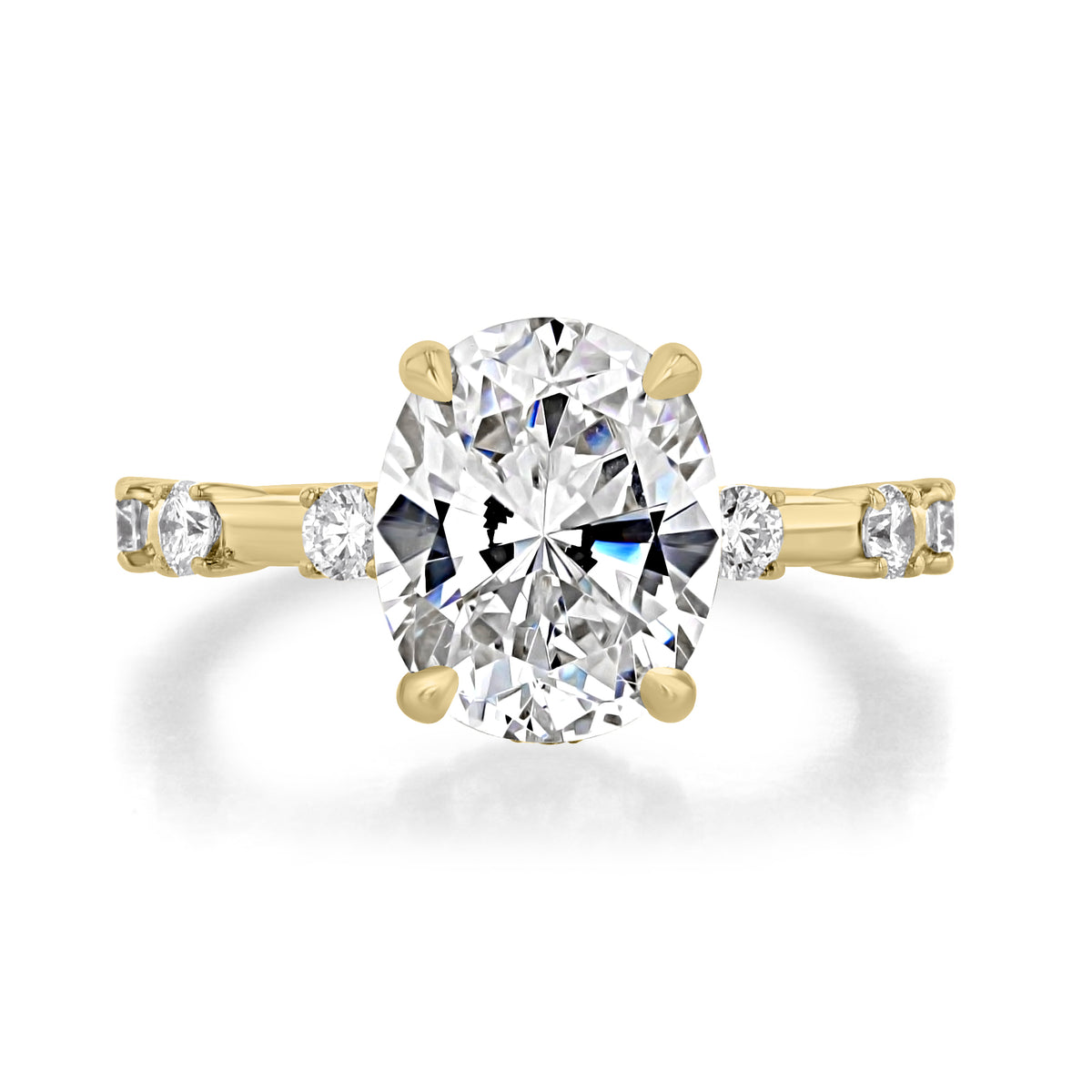 Miramar | Oval Prong-Set Engagement Ring featuring an oval-cut diamond on a yellow gold band with three smaller round-cut diamonds on each side.