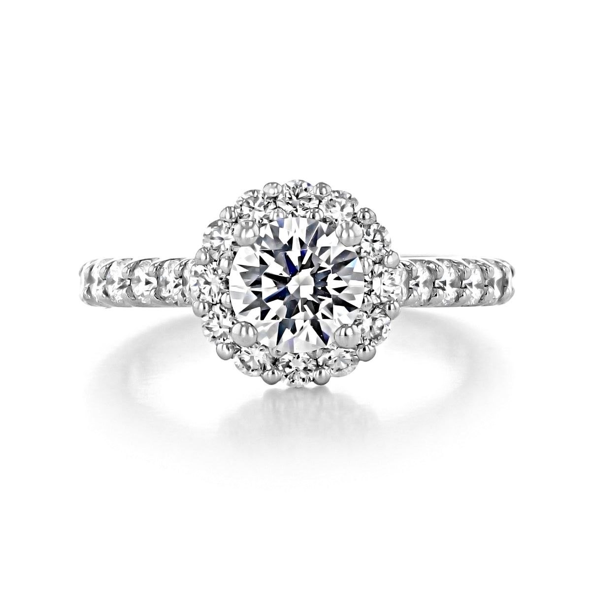 Paloma | Round Halo Engagement Ring featuring a round center diamond, a halo of smaller diamonds, and pavé-set diamonds along the prong-set band.