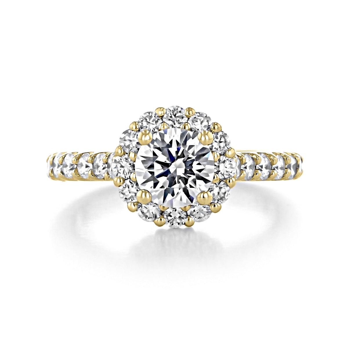 Paloma | Round Halo Engagement Ring featuring a gold band with a round-cut center stone surrounded by a halo of smaller prong-set diamonds, with additional diamonds lining the band.