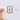 Larkin | Three-Stone Engagement Ring by Gabriel & Co. in rose gold featuring an emerald cut center stone, a rectangular halo of small diamonds, and a tapered baguette diamond on each side.