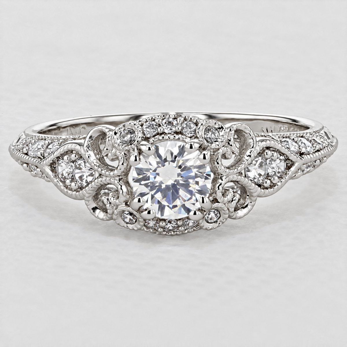 Abel | Halo Engagement Ring by Gabriel & Co. featuring a round-cut diamond in a decorative filigree setting with small pavé diamonds along the band.