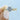 A gold Coastal Crescent | Round Solitaire Engagement Ring - P1022RD8Y with a round center stone and a vintage-inspired, pavé-set diamond band held between two fingers.