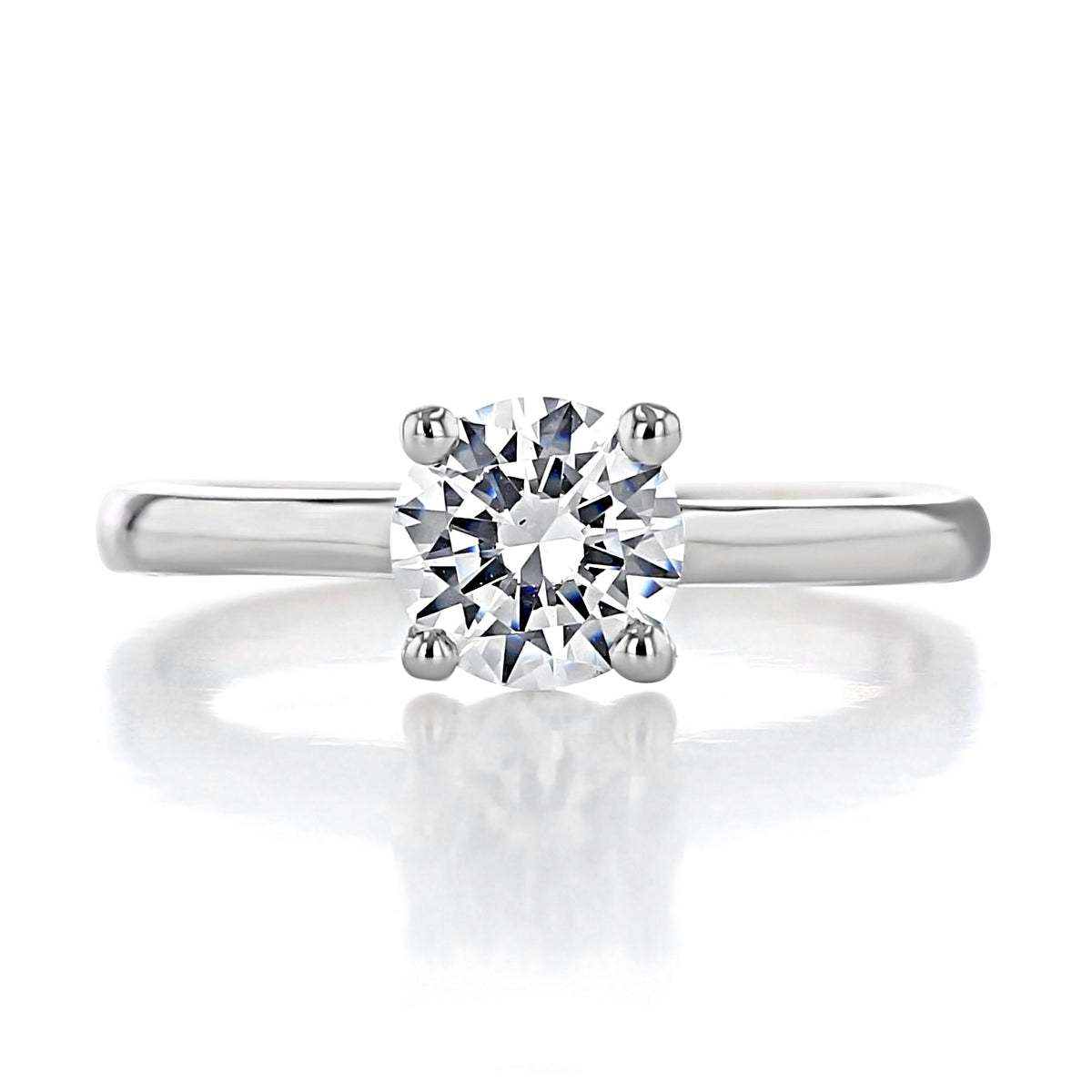 Amara Round Solitaire Engagement Ring by Icing On The Ring featuring a round-cut gemstone in a four-prong setting on a smooth metal band.