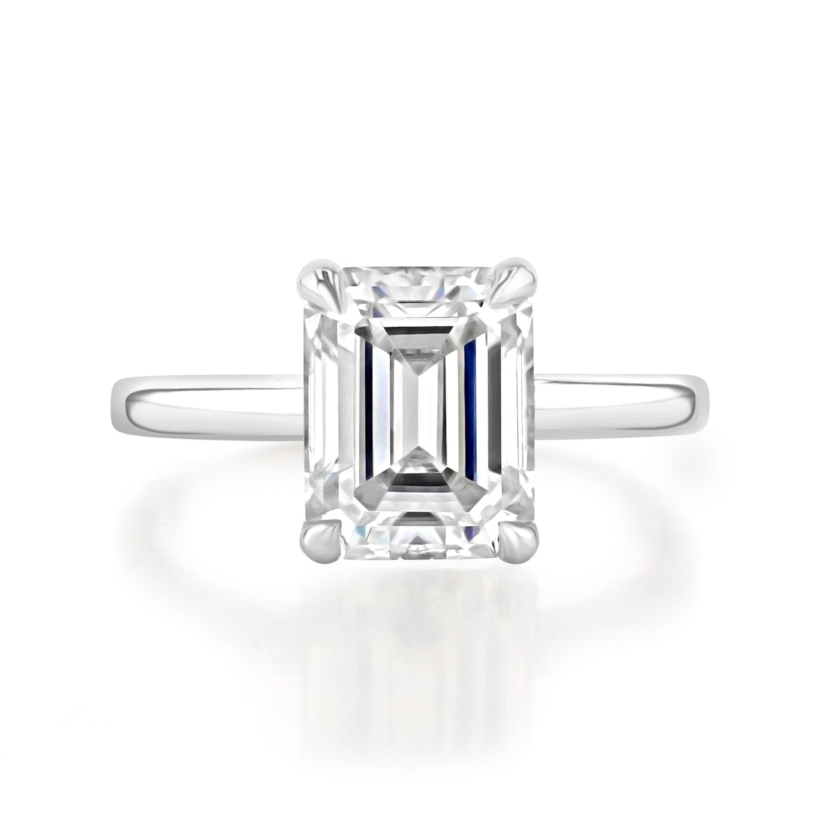 The Laurel emerald solitaire engagement ring by Icing On The Ring features a classic platinum setting with a rectangular emerald-cut diamond held by four prongs.