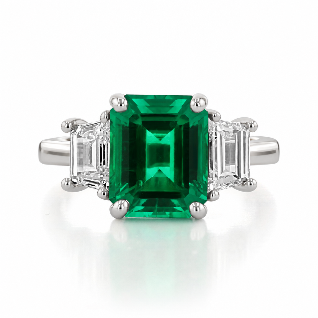 Emerald Three-Stone Engagement Ring | TR93 featuring a large, lab-grown emerald-cut green stone flanked by two emerald-cut diamonds on a 14K white gold band.