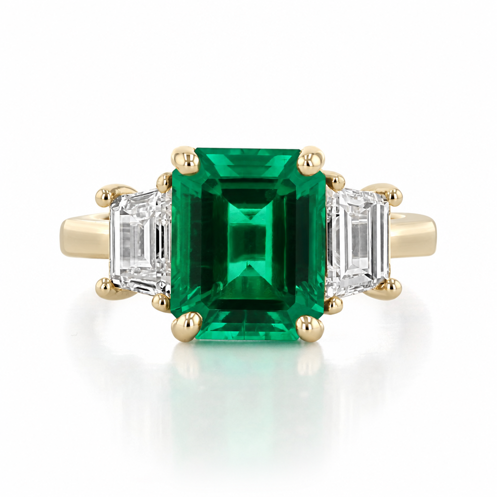 Emerald Three-Stone Engagement Ring | TR93 featuring a lab-grown emerald center flanked by two baguette-cut diamonds on a 14K yellow gold band.