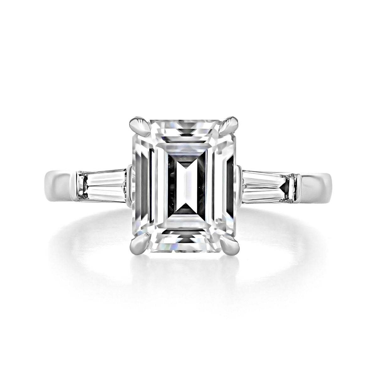 Vivienne emerald three-stone engagement ring featuring an emerald cut center stone flanked by two tapered baguette side stones on a 14k white gold band.