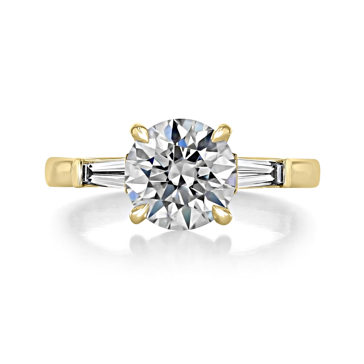 Vivienne | Round Three-Stone Engagement Ring in 14k yellow gold, featuring a large round-cut center stone flanked by a tapered baguette diamond on each side.
