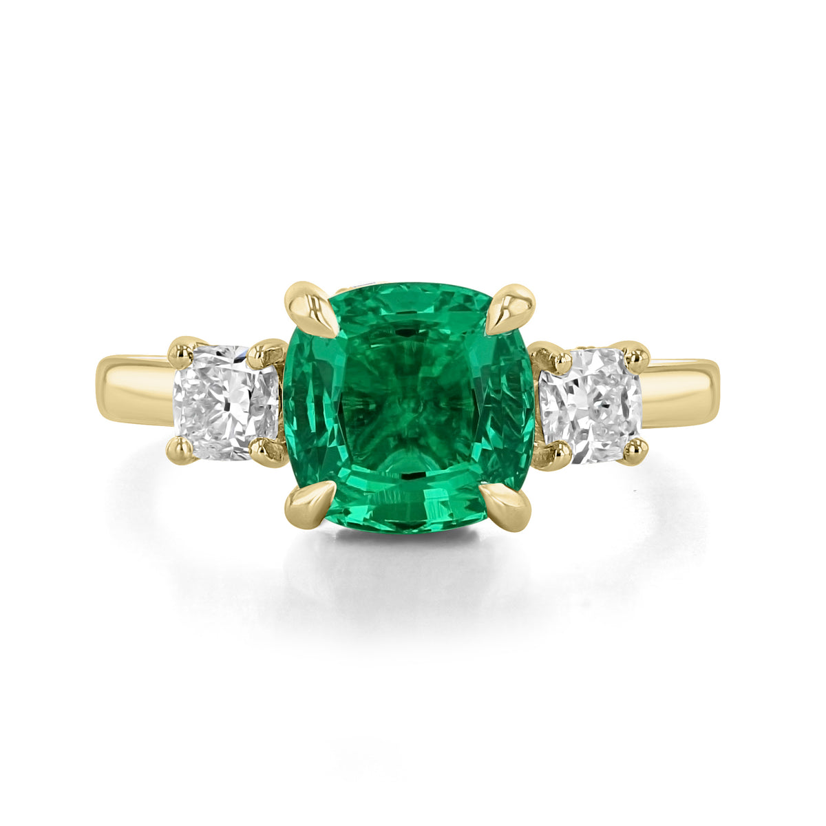Icing On The Ring Emerald Three-Stone Engagement Ring | TR97 featuring a yellow gold cushion-cut emerald flanked by two square-cut diamonds.