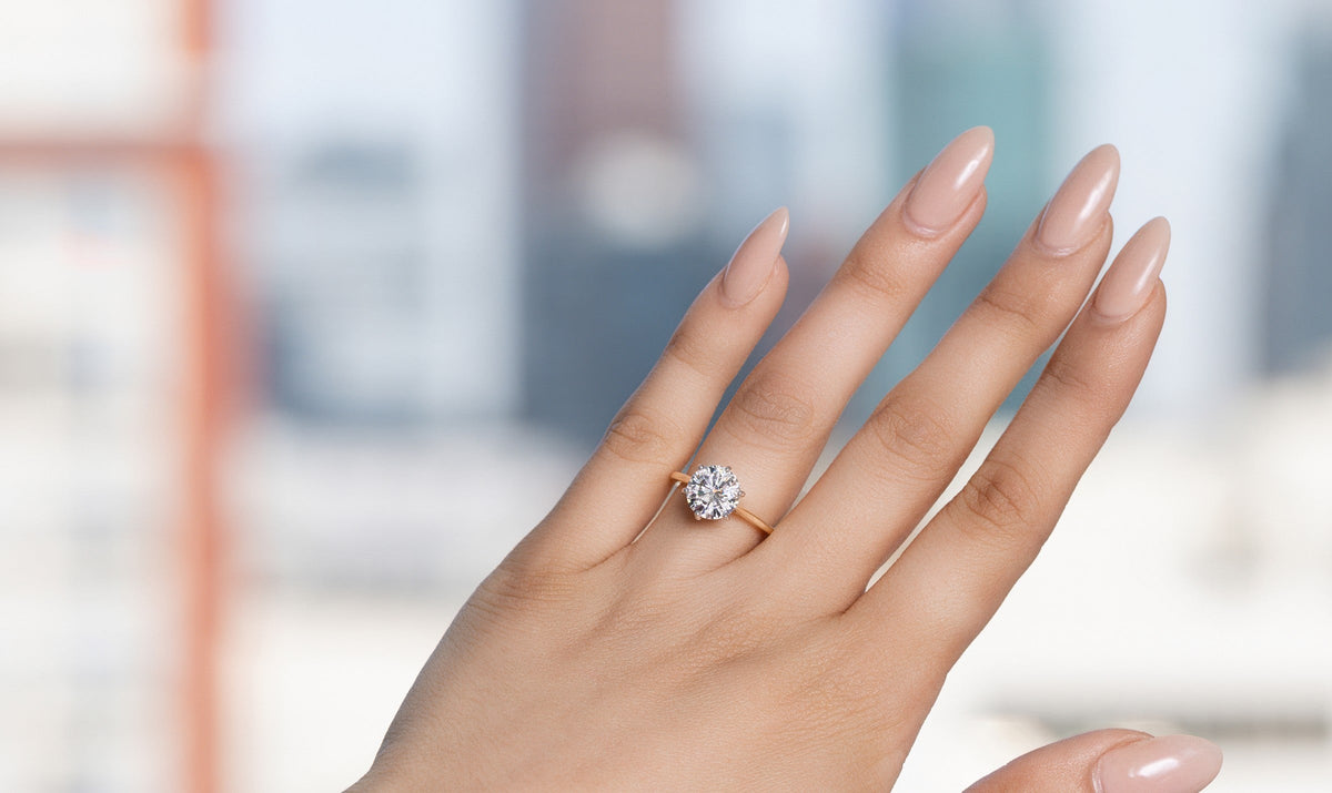 Hand wearing a round diamond solitaire proposal ring