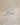 A pair of round-cut diamond stud earrings in a silver-toned setting, resting on a textured beige surface.