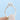 A hand holds a silver Geneva | Round Micro-Prong Engagement Ring, featuring a round diamond center stone set in four prongs above a band lined with micro-prong accent diamonds.