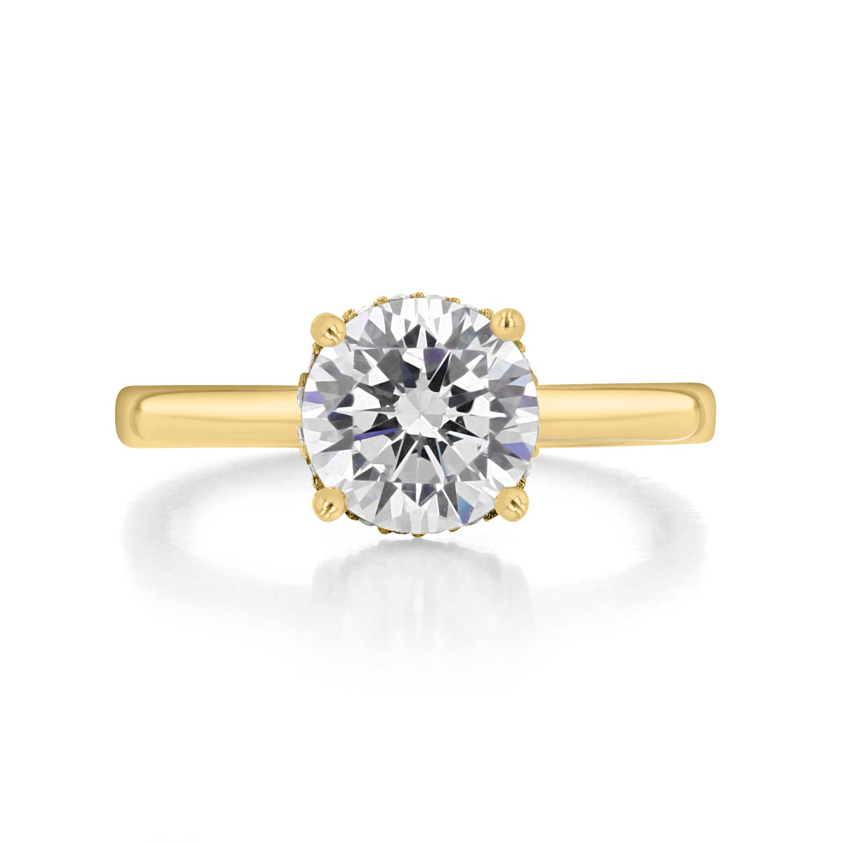 Kaia Round Solitaire Engagement Ring by Icing On The Ring, featuring an 18K yellow gold band with a round diamond center stone held by four prongs.