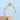 Aurora | Round Twist Engagement Ring in gold featuring a round center diamond in an East-West prong setting on a pavé-set twisted band held between fingers.