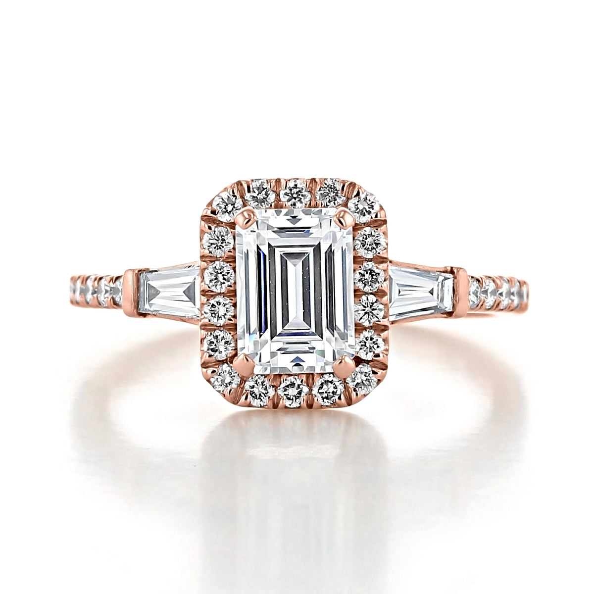 Larkin | Three-Stone Engagement Ring by Gabriel & Co. featuring a rectangular emerald cut center diamond, a halo of small round diamonds, and two baguette-cut side stones on a gold band.