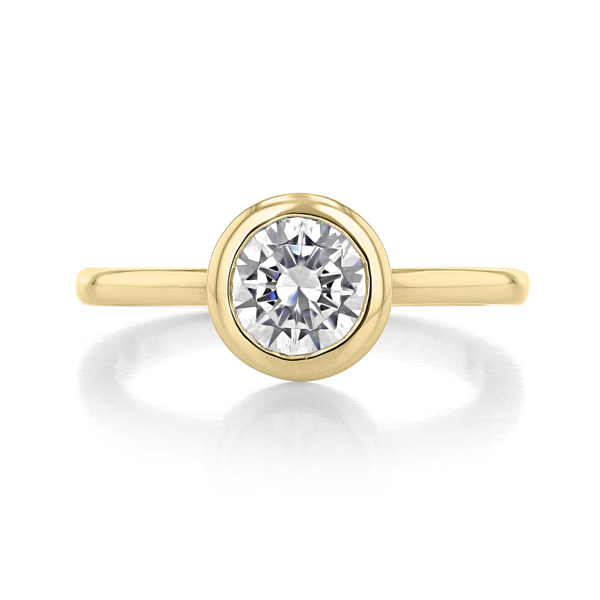 A round brilliant-cut diamond in a gold bezel solitaire setting on a thin gold band, featuring the Danhov Per Lei | Bezel Engagement Ring - LE100.