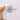 A 14k rose gold Coastal Crescent | Cushion Solitaire Engagement Ring - P1032CU8Y by Tacori featuring a round center diamond within a cushion-shaped halo of smaller stones, held between two fingers.