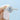 A Coastal Crescent | Round Solitaire Engagement Ring - P103RD65 held between two fingers, featuring a round center stone, a halo of smaller stones, and pavé accents on the band.