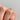 A hand holds an Icing On The Ring Solitaire Proposal Ring | SO38, a 14k rose gold solitaire engagement ring featuring a princess-cut diamond.